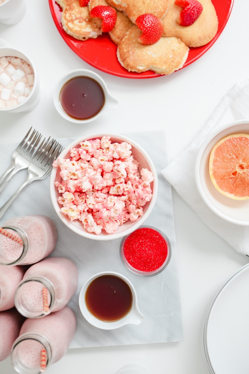 Valentine's Day Brunch that the entire family with love... complete with the cutest EASY heart shaped pancakes and strawberries, pink smoothies and a pink candied popcorn recipe! Host a galentine's brunch or serve your valentines a breakfast they'll remember!