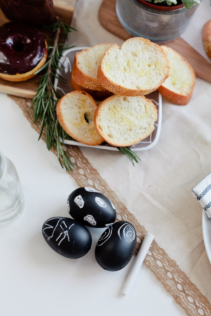 Easter brunch ideas |Easter Brunch Ideas by popular Florida lifestyle blog, Fresh Mommy Blog: image of sliced bread in a square white ceramic dish an some black chalkboard eggs with designs drawn on them in white chalk.  