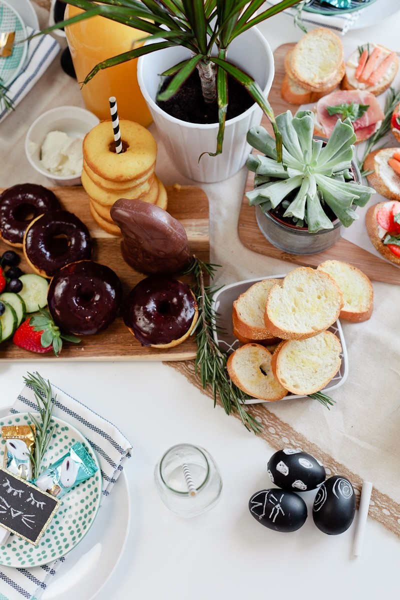 Easter brunch ideas |Easter Brunch Ideas by popular Florida lifestyle blog, Fresh Mommy Blog: image of a wooden cutting board filled with cucumber slices, strawberries, blueberries, glazed donuts, chocolate frosted donuts, and a chocolate bunny. 