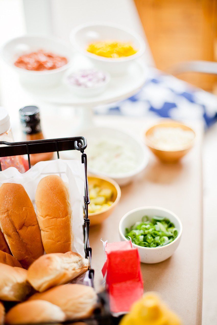 Red White and Blue fun, and a DIY Americana Hot Dog Bar! Set up toppings and flavors for all kinds of hot dogs from around the U.S. Chicago style, Boston, Detroit, Philly, Carolina hot dog and more! |  Hot Dog Bar by popular Florida lifestyle blog, Fresh Mommy Blog: image of hot dog buns in a black wire basket. 