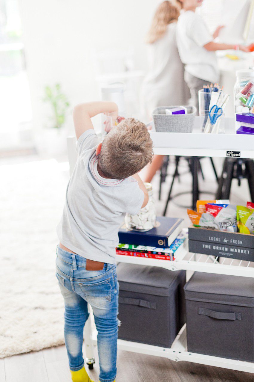 How to Get Ready for School: 5 Sensational Strategies to Make Easy on your Family by popular Tampa life and style blog, Fresh Mommy: image of a young boy grabbing supplies off of a homework cart.