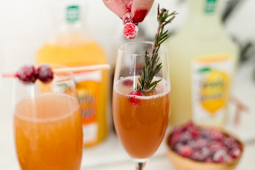 A mimosa bar makes a perfect addition to breakfast or brunch, and makes it easy on the hostess as guests can happily serve themselves. Just a small tweak makes it family-friendly, plus incredibly simple 2-ingredient sparkling sugared cranberries make a beautiful topper – and perfect for holiday snacking or beautiful on desserts!