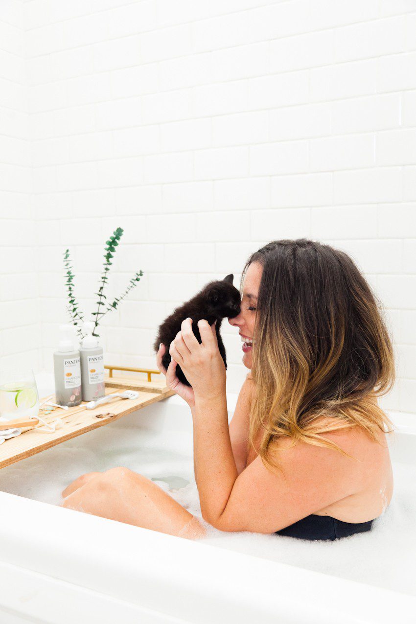 Kitten Care Tips: 5 Essentials you Need to Raise a Cat by popular lifestyel blogger Tabitha Blue of Fresh Mommy Blog: image of woman sitting in bubble bath and holding a black kitten.