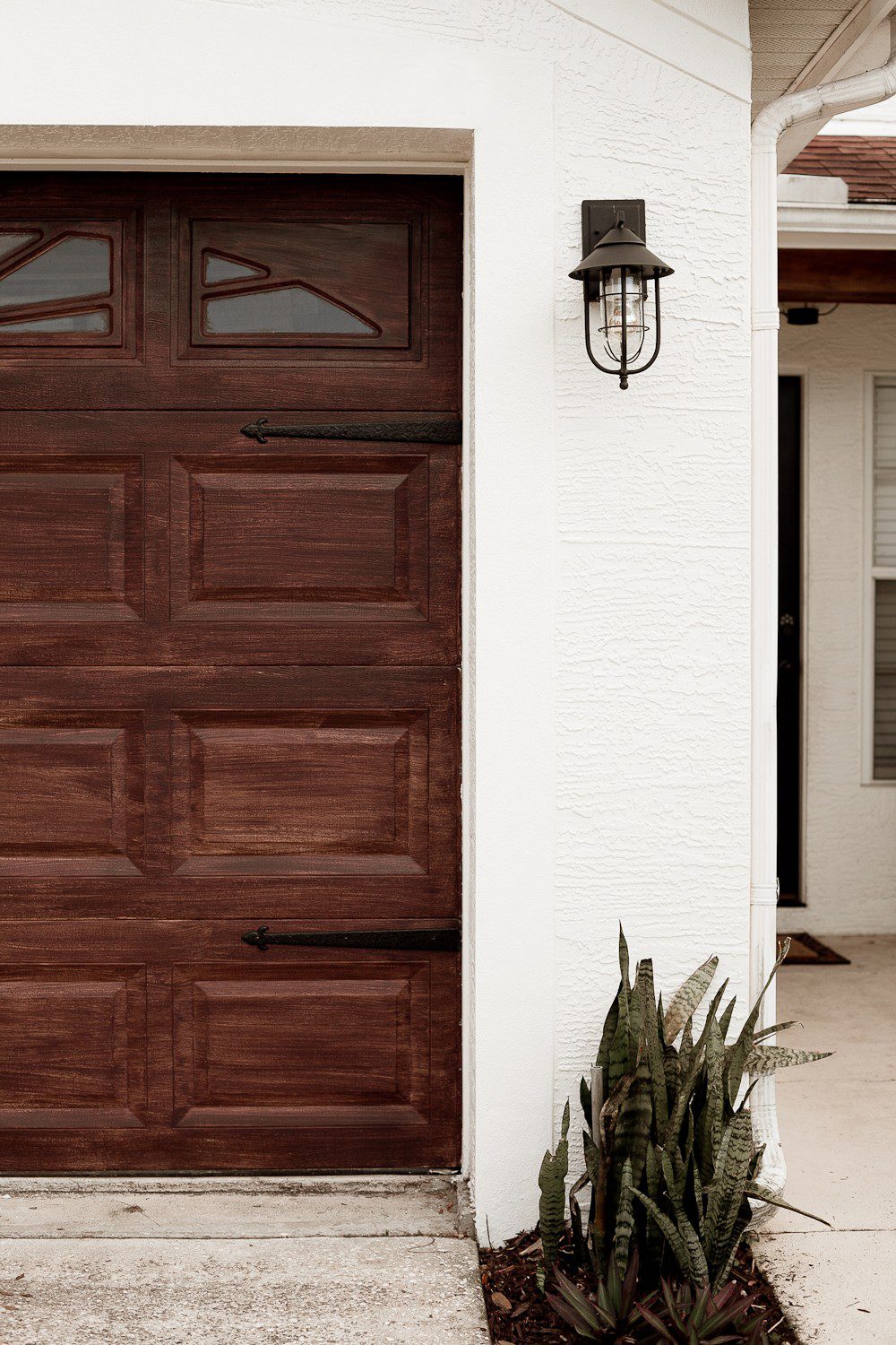Transform your garage door to a gorgeous faux wood door with this easy gel stain DIY garage door makeover by popular diy blogger Tabitha Blue of Fresh Mommy Blog: image of white house with a faux wood garage door.