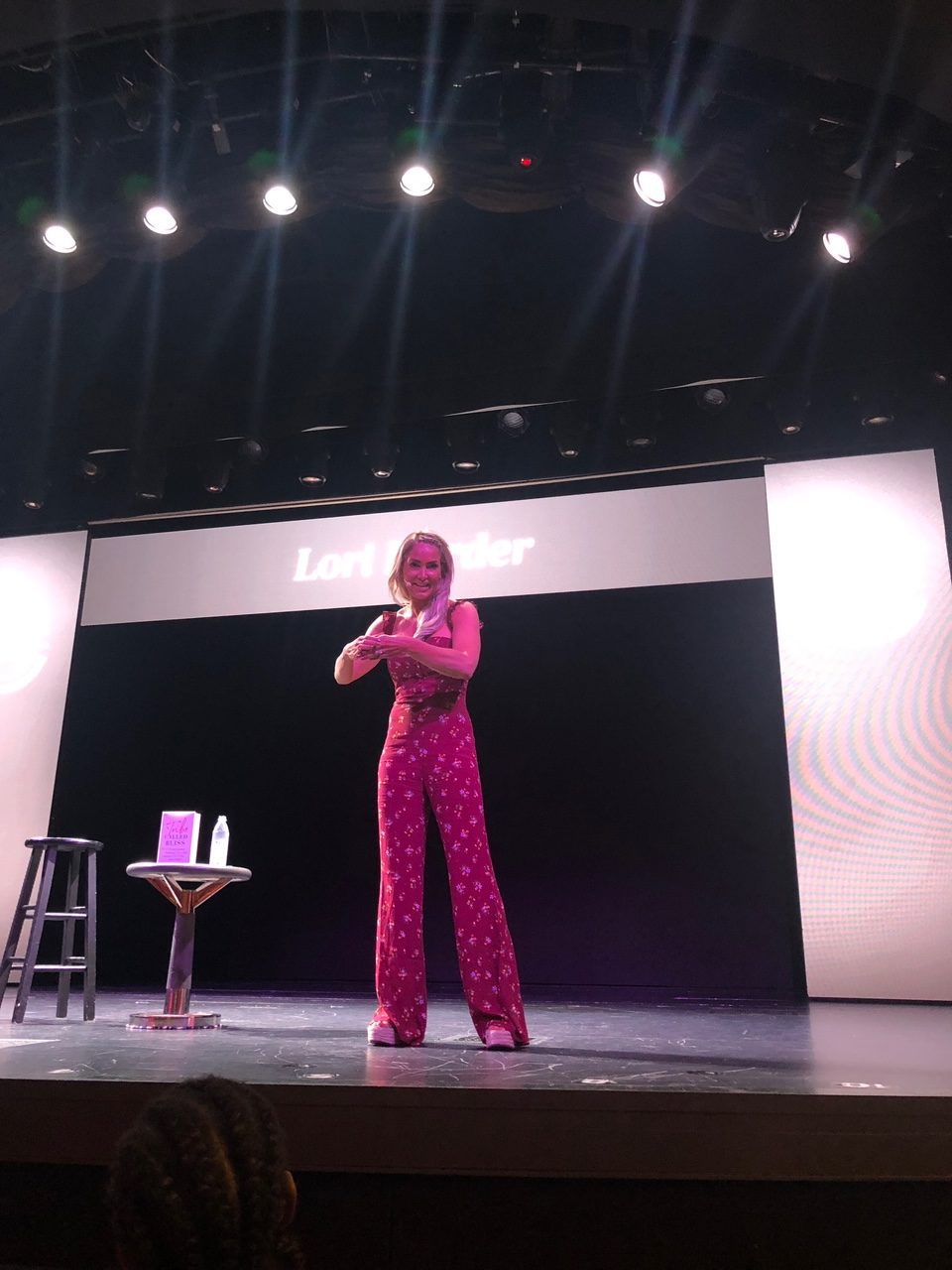 5 Amazing Reason to go on a Holland America cruise with Oprah Magazine by popular US lifestyle blog Fresh Mommy Blog: image of woman in maroon jumpsuit standing on stage and giving a presentation.