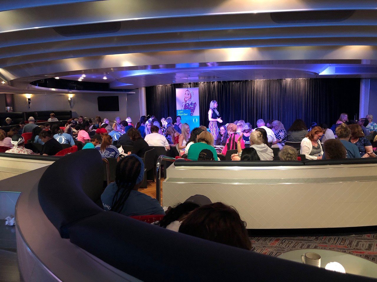 5 Amazing Reason to go on a Holland America cruise with Oprah Magazine by popular US lifestyle blog Fresh Mommy Blog: image of Lori Harder giving a presentation to a group of people on Holland America cruise ship.