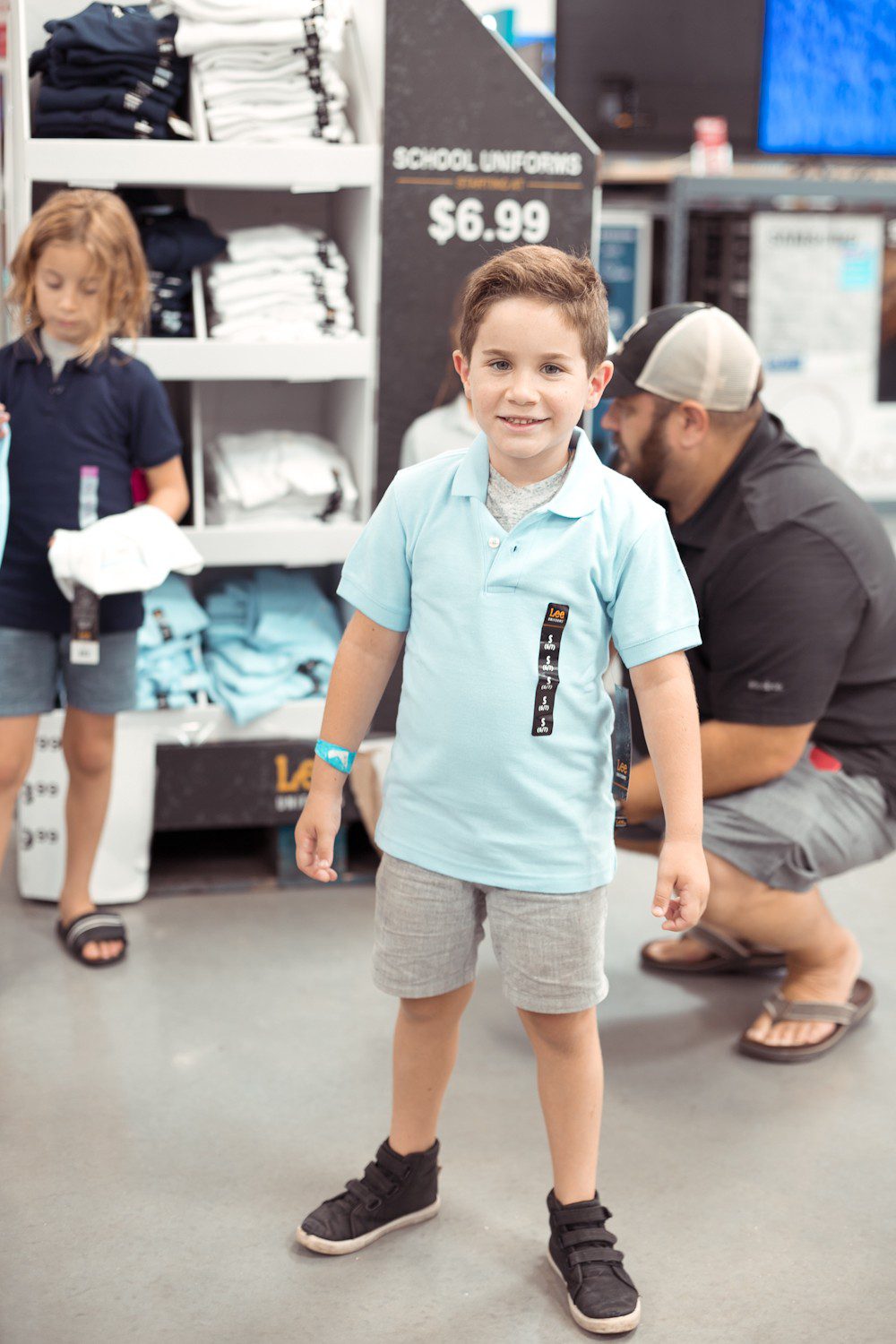 5 Sensational Strategies to Make Getting Ready for School Easy | How to Get Ready for School: 5 Sensational Strategies to Make Easy on your Family by popular Tampa life and style blog, Fresh Mommy: image of a dad helping his two young sons try on a blue Lee polo shirt.