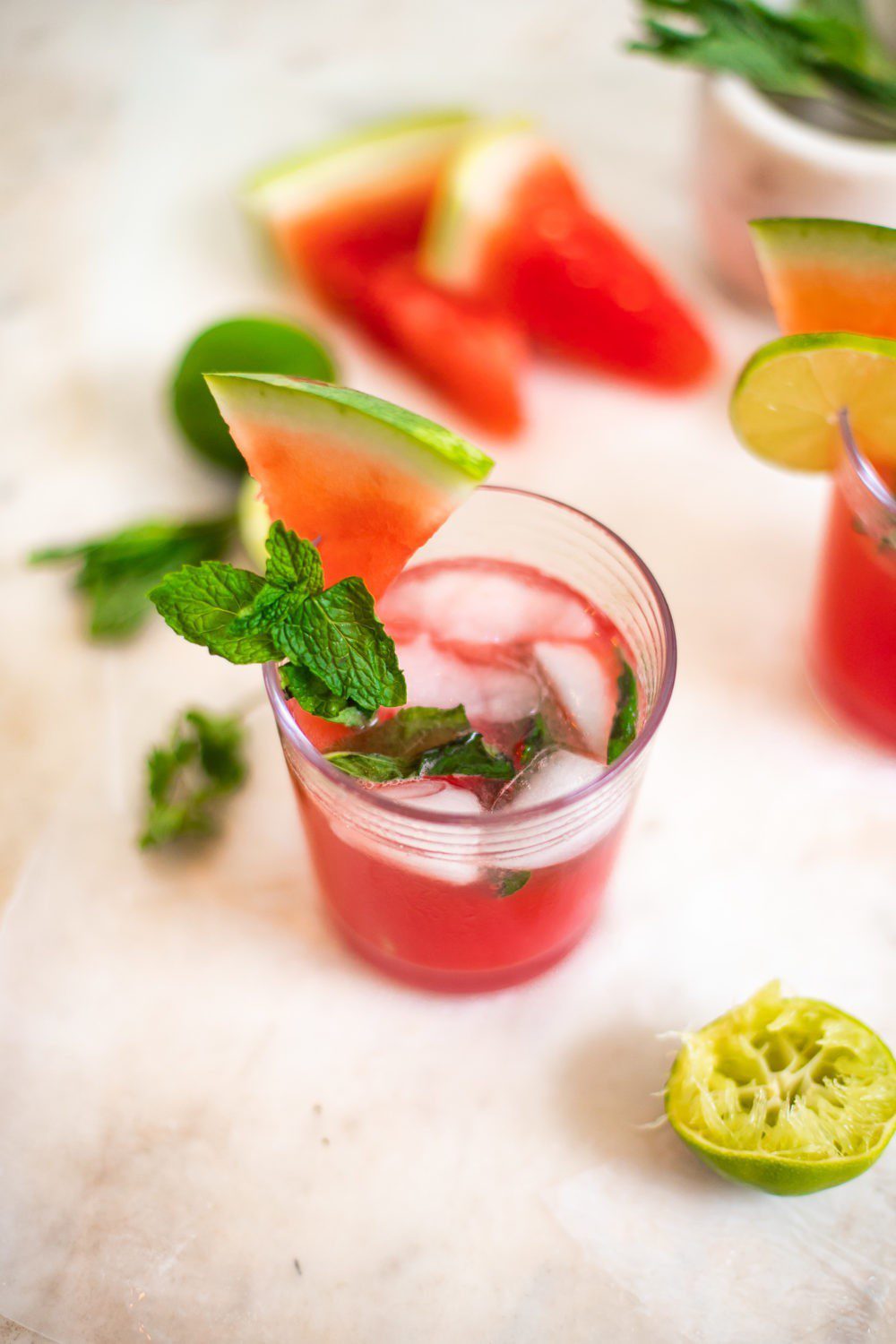 Refreshingly Easy Summer Mocktail Recipes! by popular Florida lifestyle blog, Fresh Mommy: image of Watermelon mojiotos on a marble countertop surrounded by lime halves and watermelon slices.