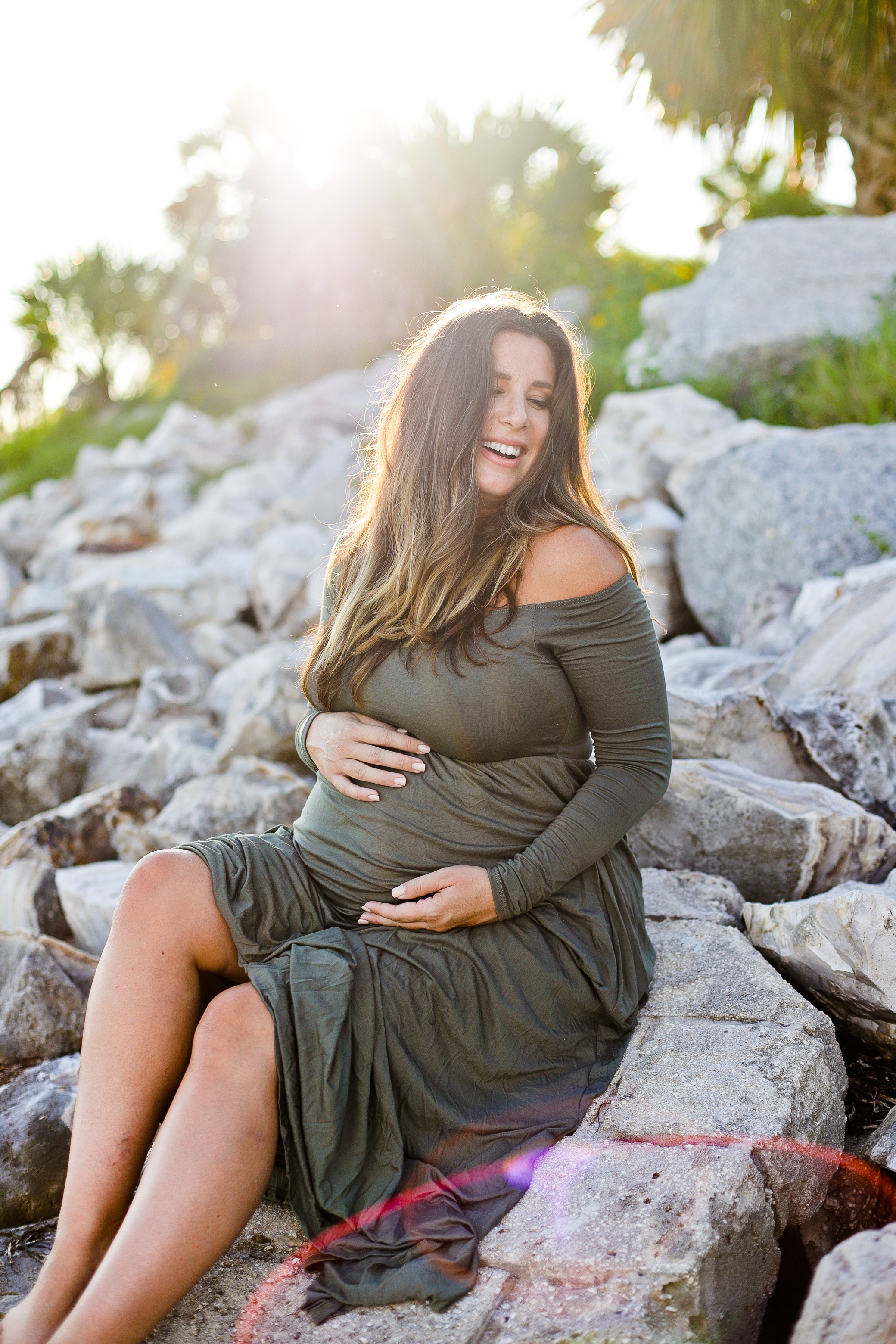 Twin Maternity Photos at the Beach | A Beach Maternity Photoshoot in Olive Green by popular Florida life and style blog, Fresh Mommy: image of a woman standing outside at the beach and wearing a Pink Blush Olive Solid Off Shoulder Maternity Maxi Dress.