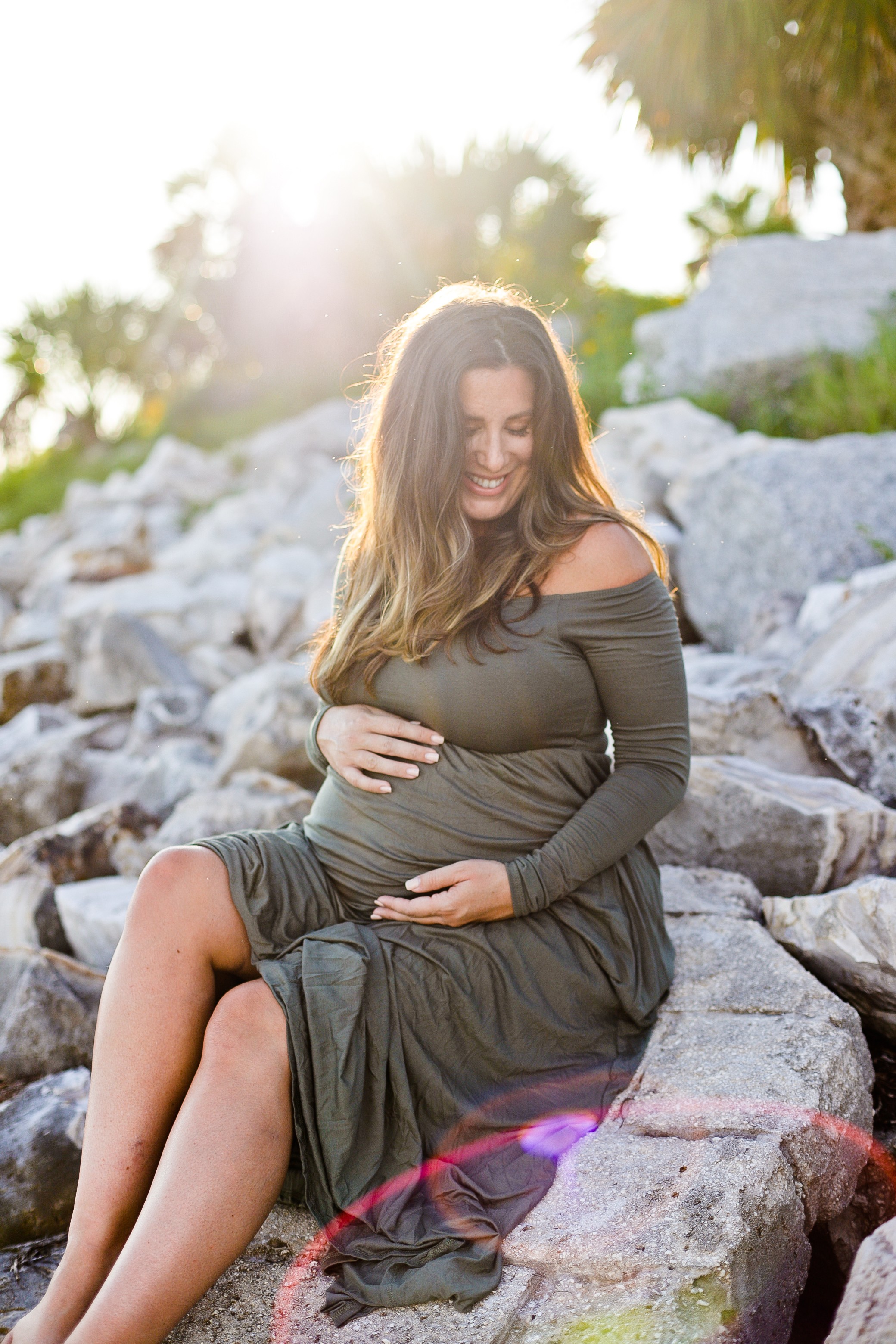 Twin Maternity Photos at the Beach | A Beach Maternity Photoshoot in Olive Green by popular Florida life and style blog, Fresh Mommy: image of a woman standing outside at the beach and wearing a Pink Blush Olive Solid Off Shoulder Maternity Maxi Dress.