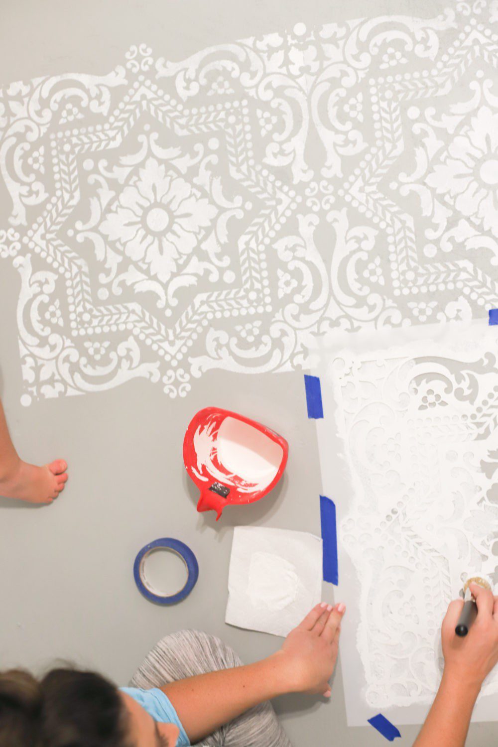 Laundry Room DIY: How to Paint a Cement Floor with Stencils | Laundry Room DIY: How to Paint a Cement Floor with Stencils by popular home decor blog, Fresh Mommy: image of a cement floor being painted with a stencil and white floor paint. 