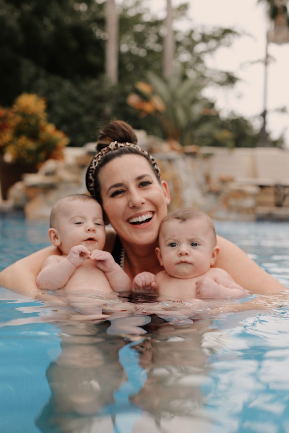 Mom holding twin babies in the pool. Spectacular Things to Do in Naples This Weekend | Spectacular Things to Do in Naples FL This Weekend by popular Florida blog, Fresh Mommy Blog: image of a mom holding her twin babies in a pool.