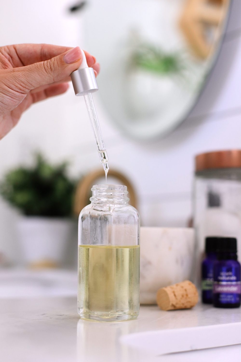 DIY Hair Growth Oil with Essential Oils Perfect for Postpartum Hair Fall. This healthy DIY scalp oil for hair growth is loaded with essential oils that boast anti-inflammatory and anti-bacterial properties that help in combating hair fall, stimulating the scalp for growth and more. | DIY Hair Growth Oil by popular Florida beauty blog, Fresh Mommy Blog: image of a woman holding a dropper filled with DIY hair growth oil. 