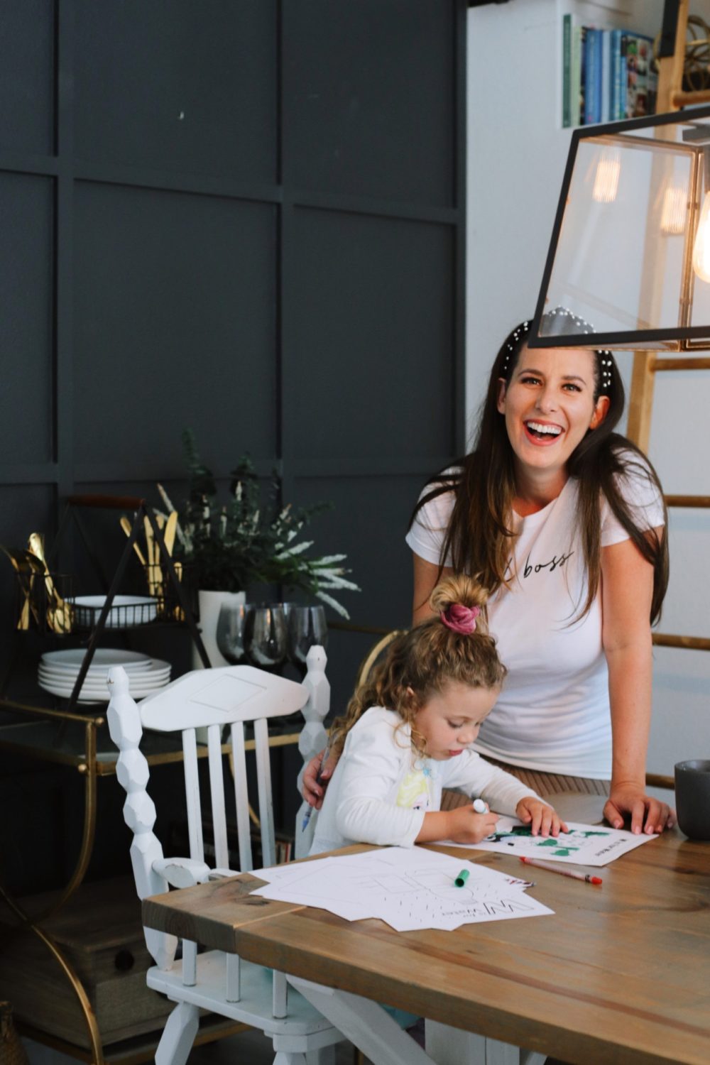 How to Survive Working With Kids at Home | Working From Home With Kids by popular Florida lifestyle blog, Fresh Mommy Blog: image of a woman standing next to her young daughter while she does school work at the table. 