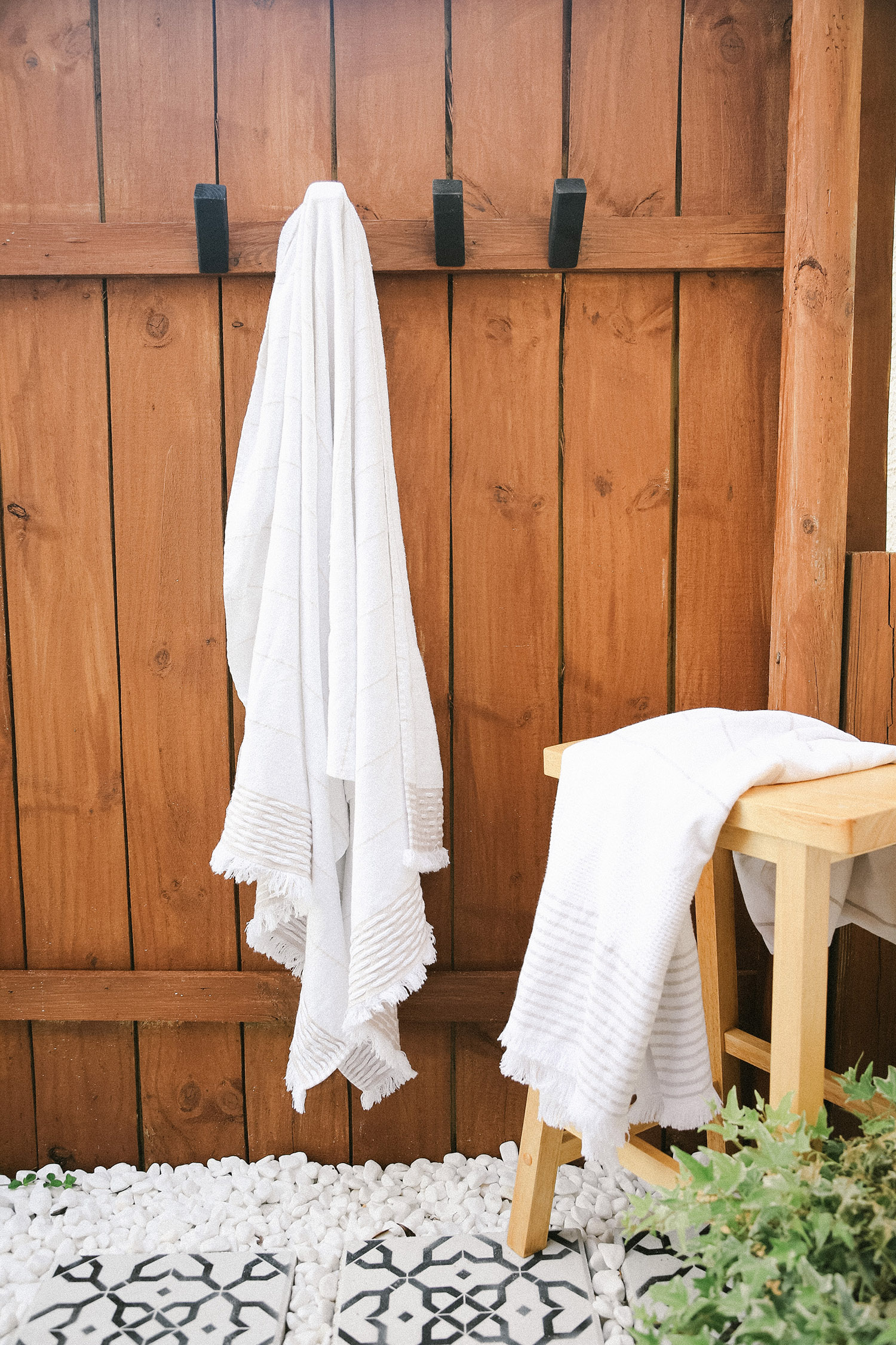 Top US lifestyle blogger Tabitha Blue shares How to Make Modern DIY Wooden Hooks for $1 Each! See the sleek wood hook design in her outdoor shower. | Wooden Hooks by popular Florida lifestyle blog, Fresh Mommy Blog: image of a white towel hanging on a wood hook that's mounted in a outdoor shower. 