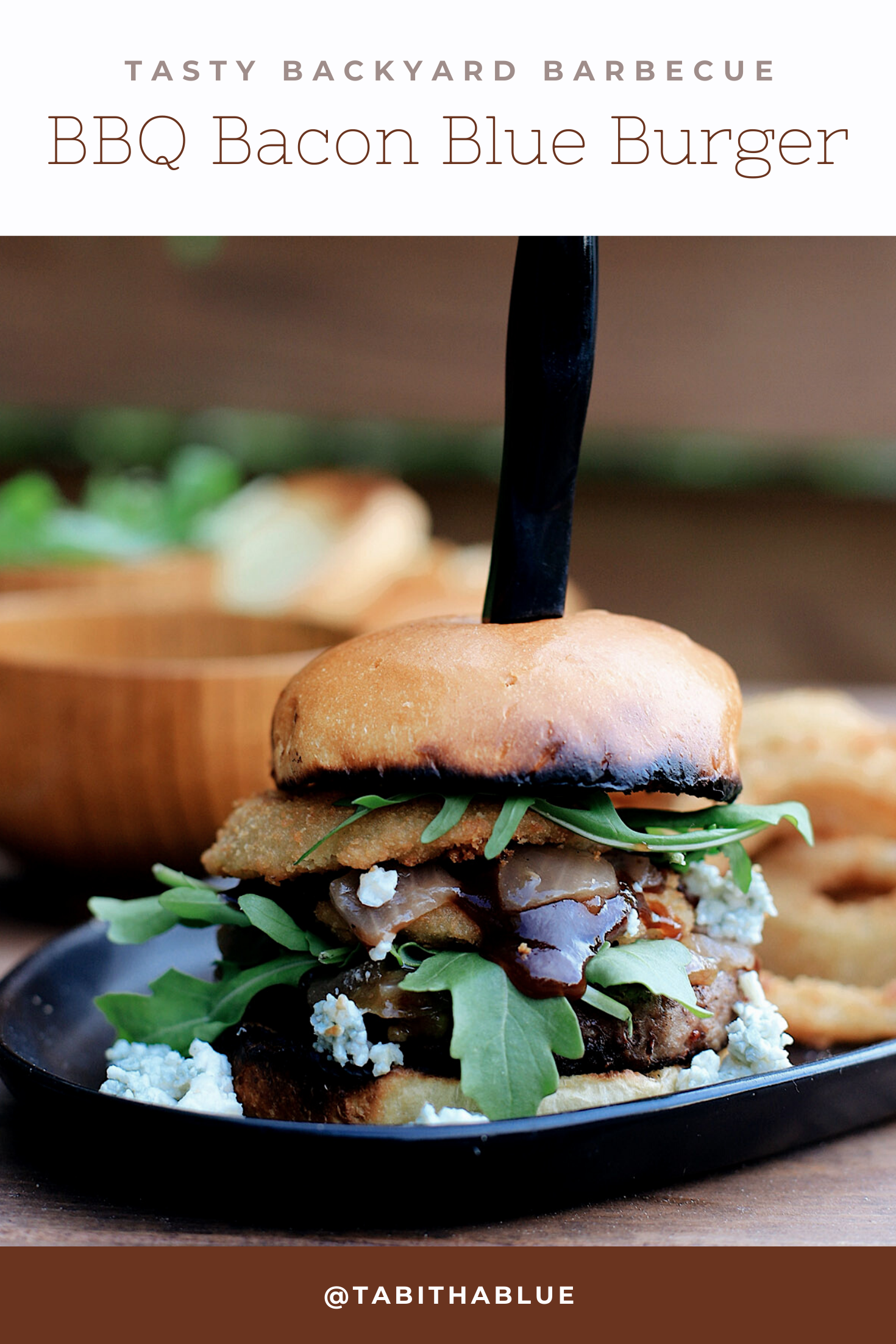 BBQ Bacon Blue Burger for a Tasty Backyard Barbecue. Not your average burger! Juicy beef burgers seasoned with a the perfect amount of spice, topped with smoked bacon jam, sweet bourbon onions, arugula, blue cheese, onion rings, BBQ sauce and a buttery grilled bun! | BBQ Burger by popular Florida lifestyle blog, Fresh Mommy Blog: Pinterest image of a BBQ Burger with bacon and blue cheese. 