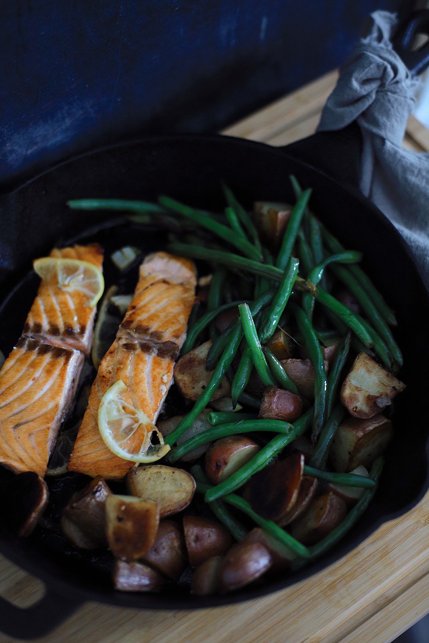 Wondering how to cook salmon? We've got such a simple and easy cast iron skillet salmon recipe with a delicious garlic lemon butter glaze. Pan seared salmon is an easy way to get it just right, every time… in fact, a kid can do it! | Salmon Skillet by possible Florida lifestyle blog, Fresh Mommy Blog: image of salmon, green beans, and potatoes in a skillet. 