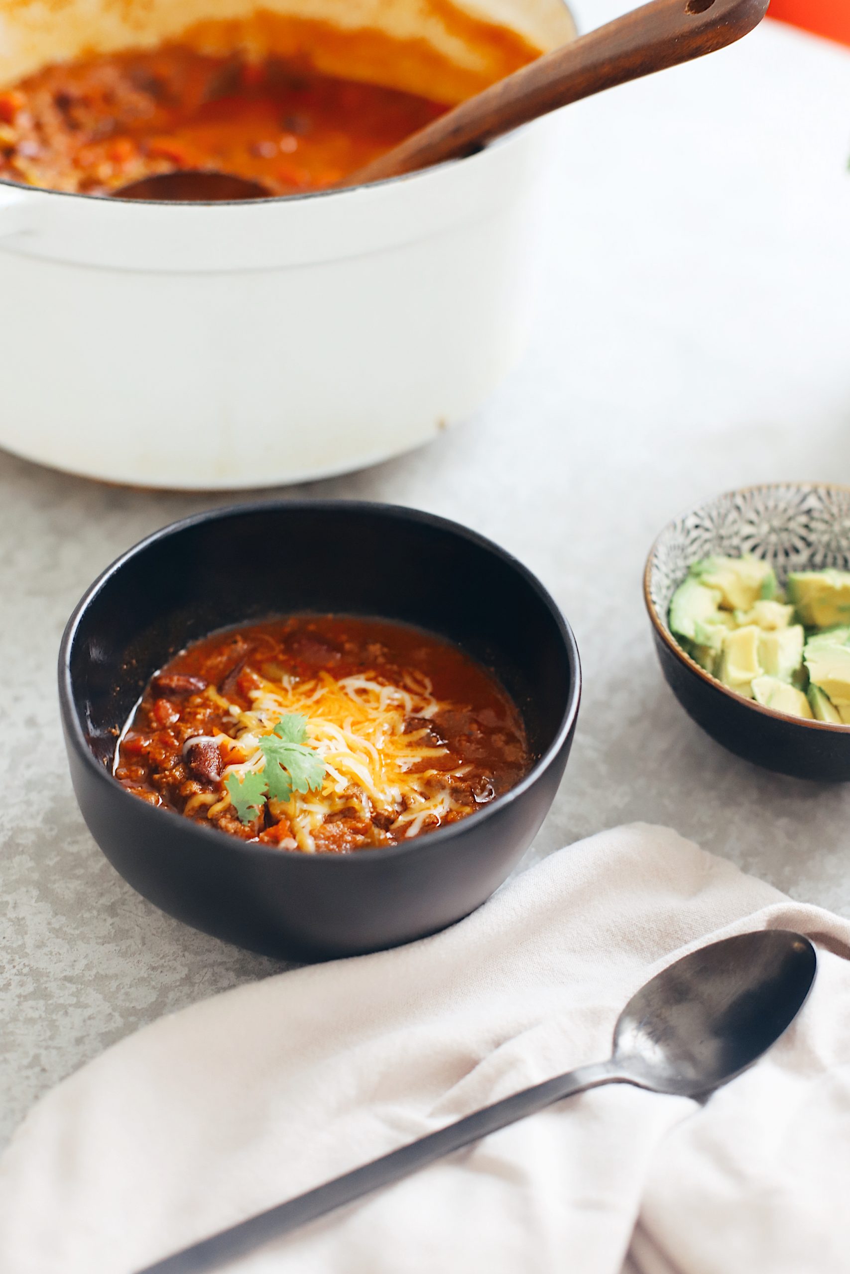 Easy Family Favorite Chili recipe! Make this delicious classic homemade chili in the crockpot or in one pot easily. It's THE BEST CHILI, and my family asks me to make it over and over. | Chili Recipe by popular Florida lifestyle blog, Fresh Mommy Blog: image of chili in a black ceramic bowl with shredded cheese on top. 