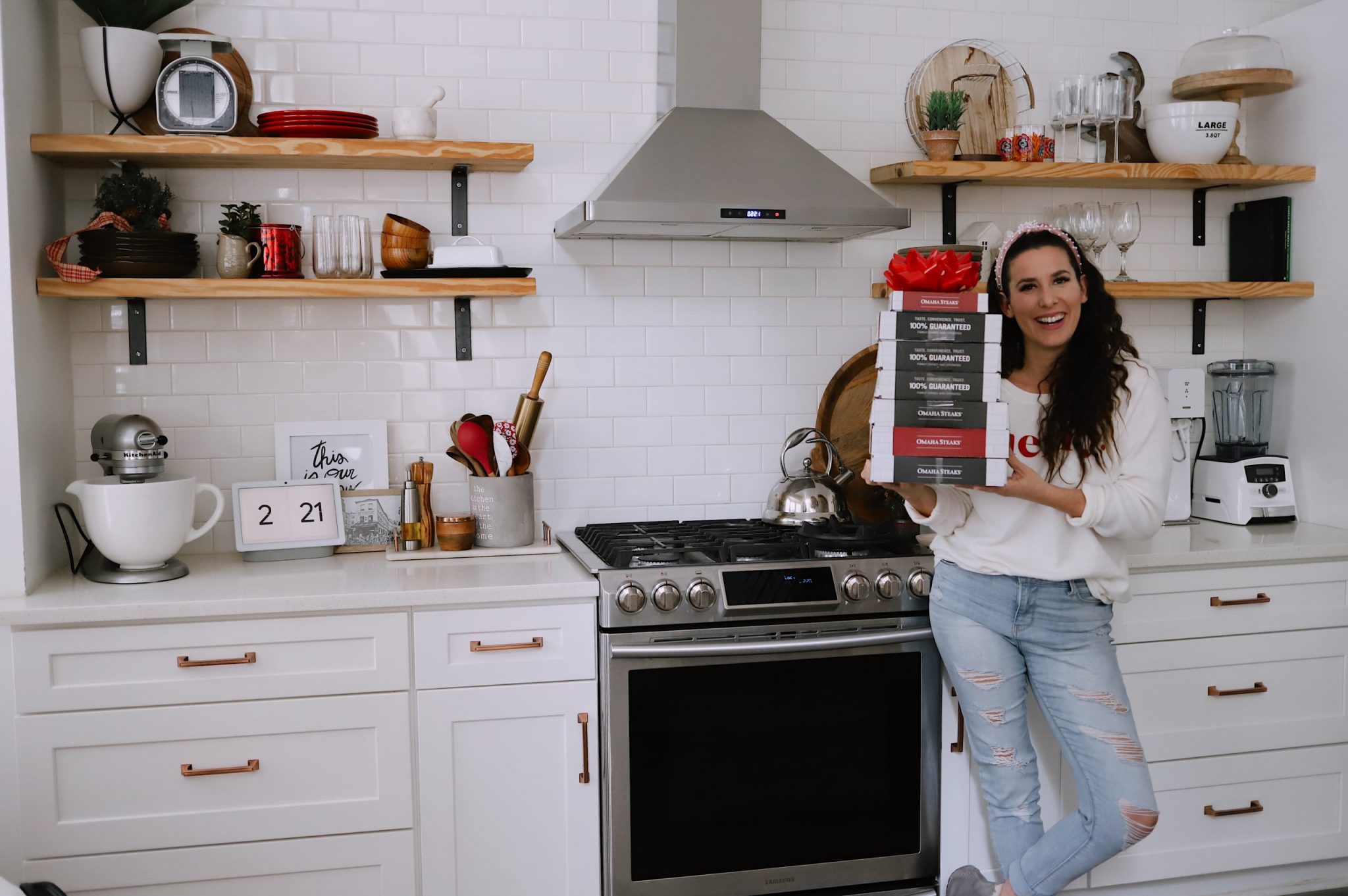Omaha Steaks Gifts by popular Florida lifestyle blog, Fresh Mommy Blog: image of Tabitha Blue standing in her kitchen and holding a stack of Omaha Steaks boxes. 