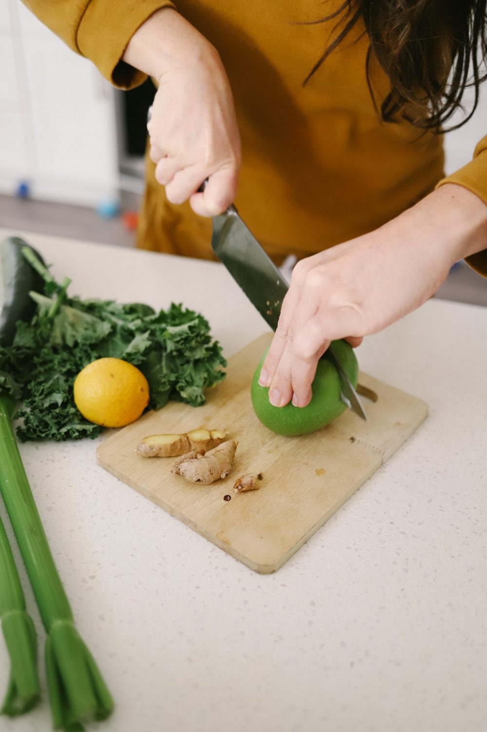 The Best Easy Clean Juicer Review for 2021: We tested easy clean juicers and this is what we found. |Easy Clean Juicer by popular Florida lifestyle blog, Fresh Mommy Blog: image of a woman cutting a green apple on a wooden cutting board. 