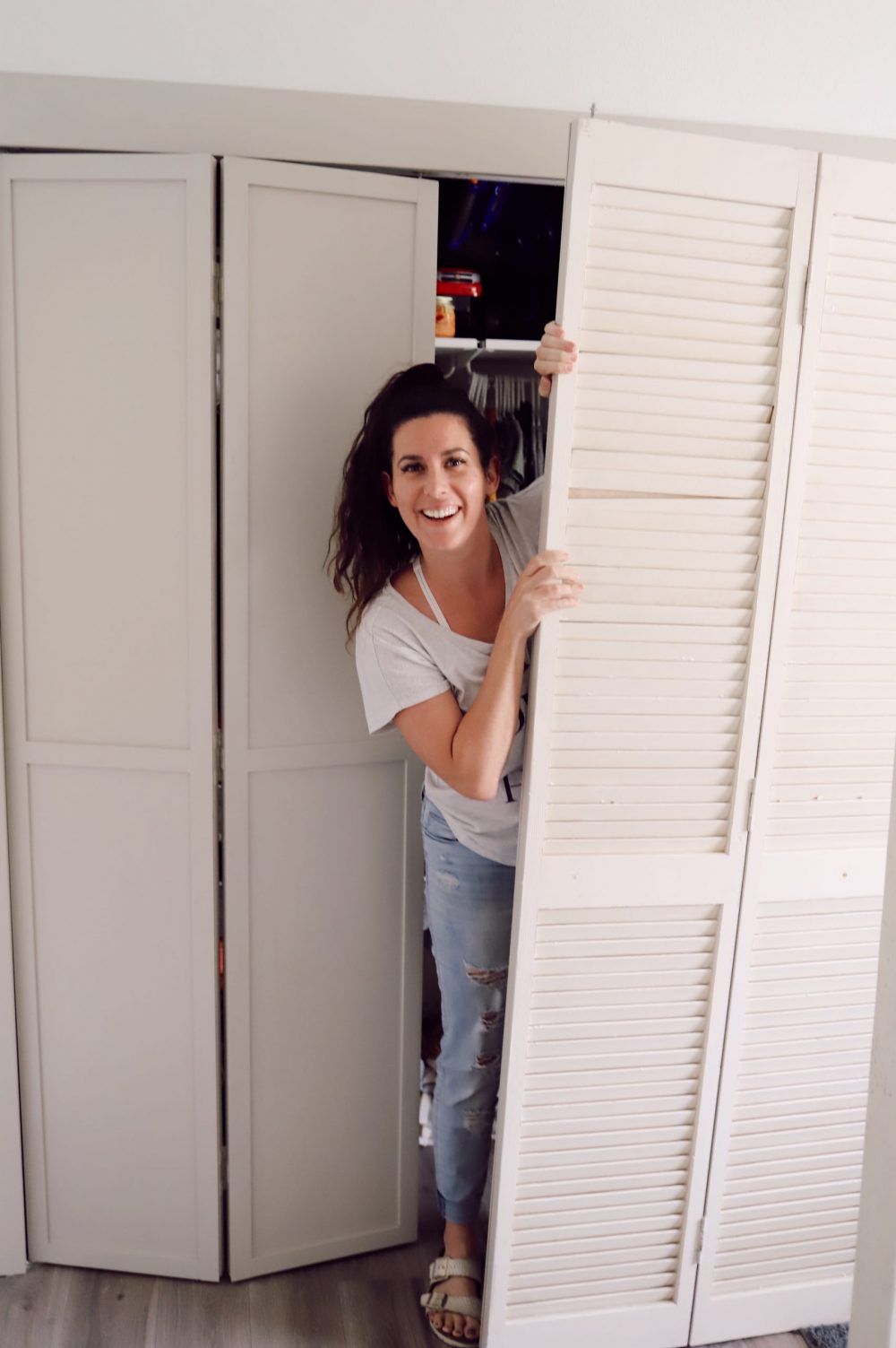 Home Refresh Ideas: DIY Closet Door Upgrade Tutorial. How to update Bi-fold closet doors on a budget. Easy how-to for updating old bifold closet doors and save money (save the hundreds it would cost to replace them!). |DIY Closet Door by popular Florida lifestyle blog, Fresh Mommy Blog: before image of a woman standing in a closet with bifold doors. 