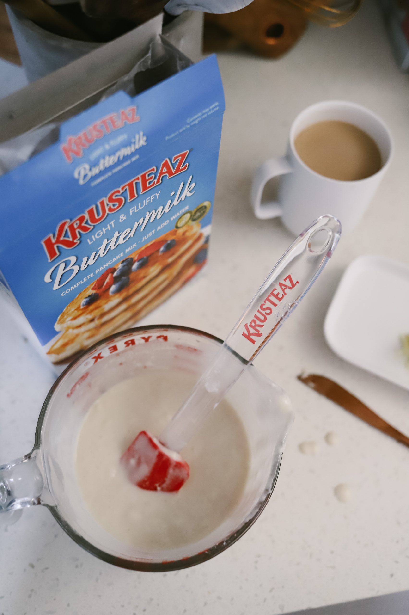 How to cook pancakes + The best Spring Breakfast Board |Pancake Board by popular Florida lifestyle blog, Fresh Mommy Blog: image of a box of Krusteaz pancake mix and a Pyrex measuring cup filled with pancake batter. 
