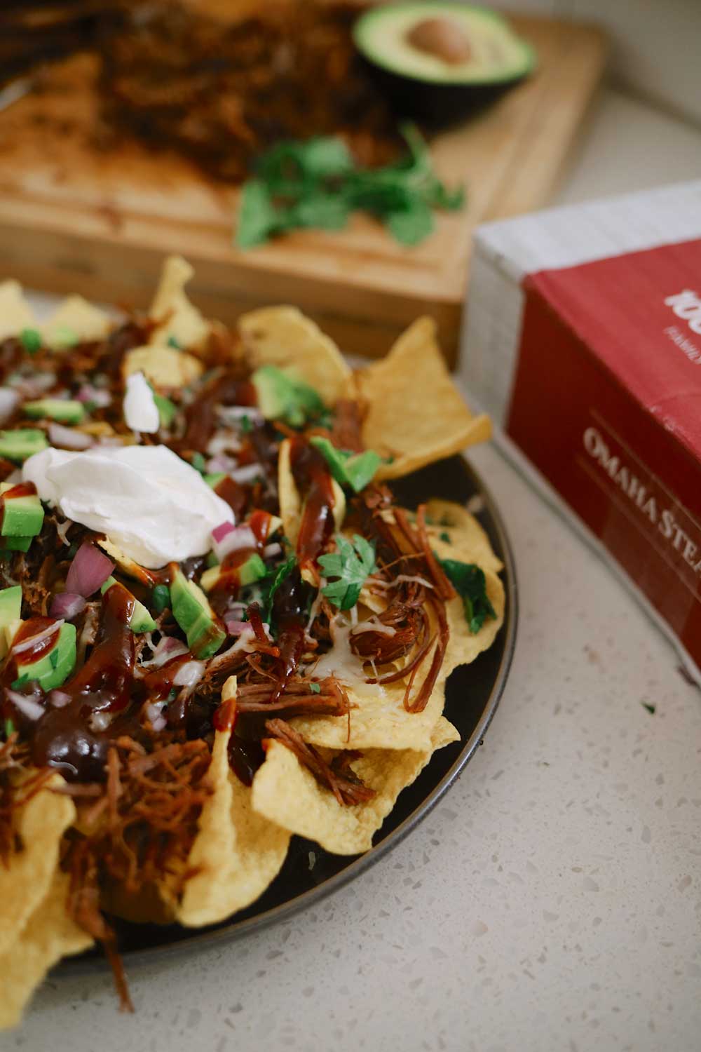 ​BBQ Brisket Slow Cooker: Easy Brisket Rub and BBQ Brisket Nacho Recipe | Slow Cooker BBQ Brisket by popular Florida lifestyle blog, Fresh Mommy Blog: image of BBQ brisket nachos with avocados, red onions, and sour cream. 