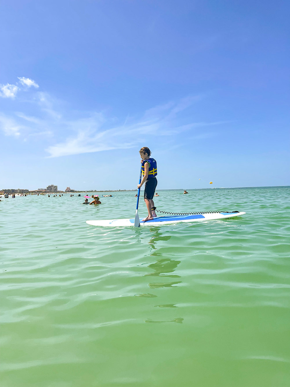 teen trying stand up paddle board at kid friendly Florida beach